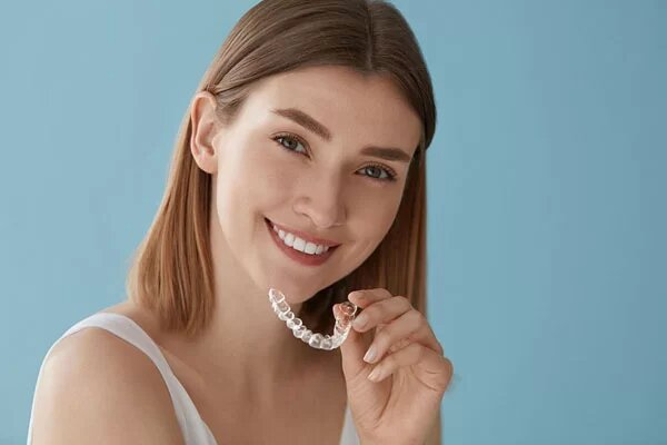 young lady holding an Invisalign aligner