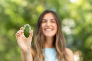 young lady holding up an Invisalign aligner